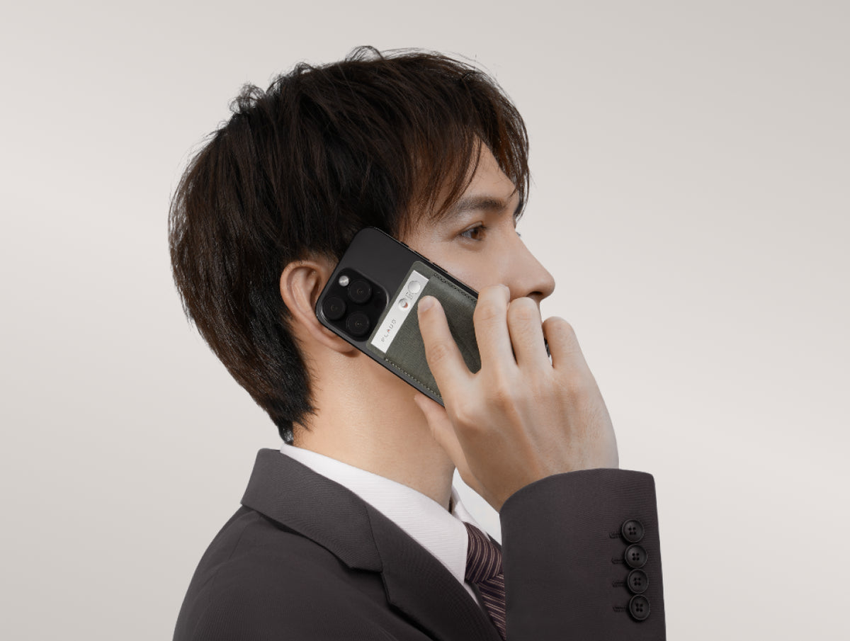 スマホ背面のPlaud Noteを操作して通話を録音する男性