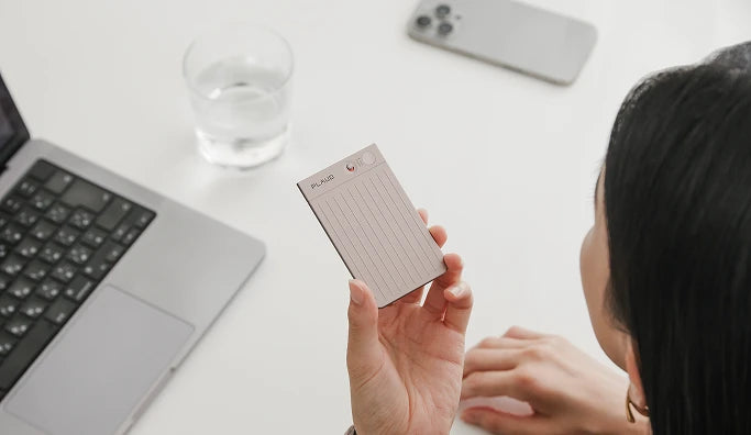 デスクでスターライトのPlaud Note Proを手に持つ女性。